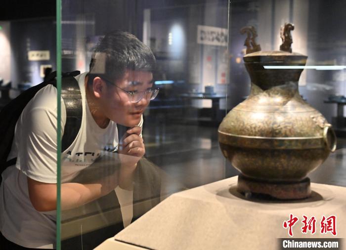一名年轻人在吉林省博物院认真观看错金银鸟篆文铜壶。　张瑶 摄