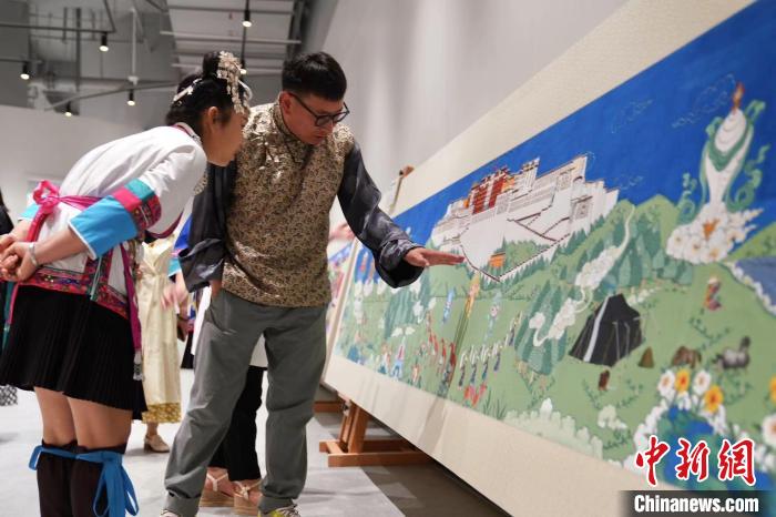 西藏画家扎西桑珠(右)在介绍画作。　钱晨菲 摄