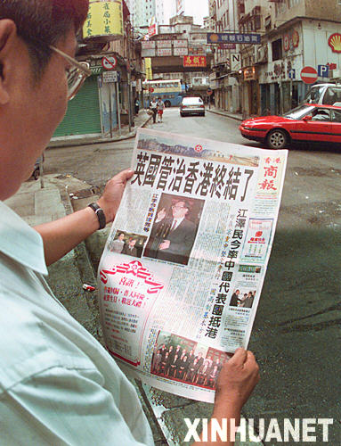 1997年7月1日凌晨 ，一位香港市民在阅读刚出版的《商报》。
