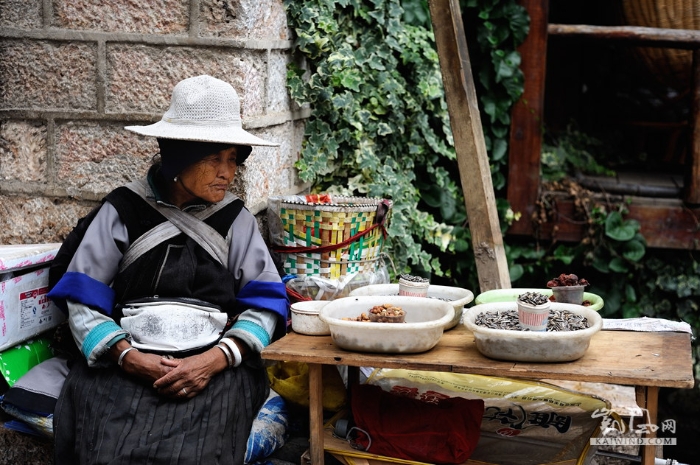 少数民族的老大妈，在街边卖着自家的炒货。服饰打扮特点分明，成为了束河古镇的一道独特风景。