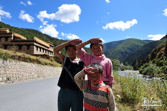 　川西赤土河谷的藏式村寨，藏族姐弟三人对外来游客和过往车辆打招呼的方式，就是敬少先队礼。