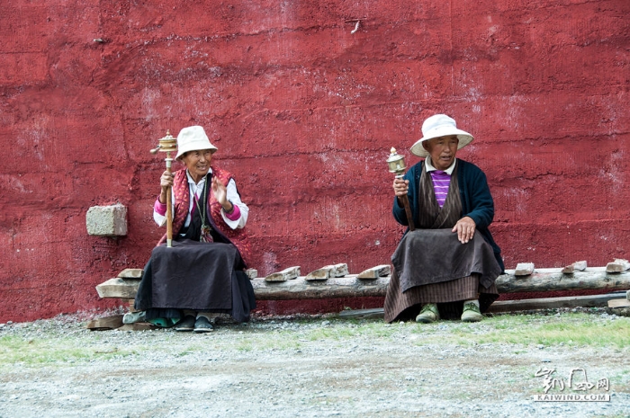 川西稻城至理塘的国道边，一个藏族大妈与一位藏族大叔坐在白塔下，转动着手中的转经筒，口中默念着经文，神