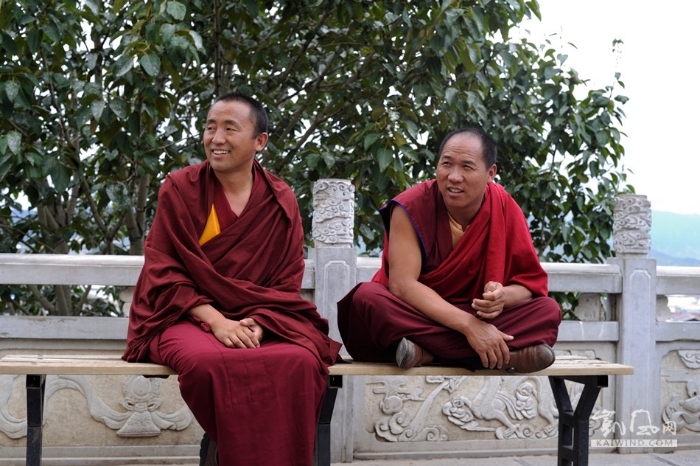 滇西北香格里拉县城龟山公园，两名喇嘛看着游客使出全身力气想要转动高21米、重60吨的世界上最大的转经
