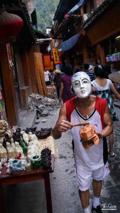 小贩戴着面具，在推销他的商品。