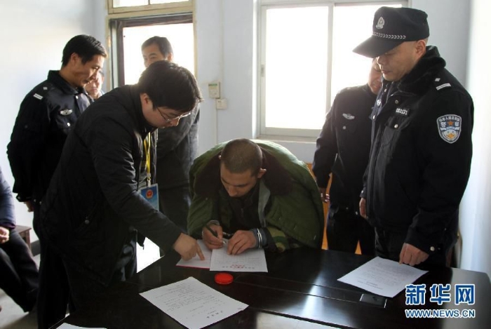 013年12月13日，被告人闵拥军（右三）在信阳市光山县看守所内签收判决书。新华社发查看大图
