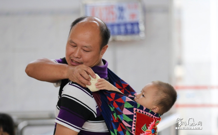 图1：8月19日，在广西柳州市融安县火车站候车室，一名旅客给孩子吃馒头充饥。（谭凯兴摄）副本