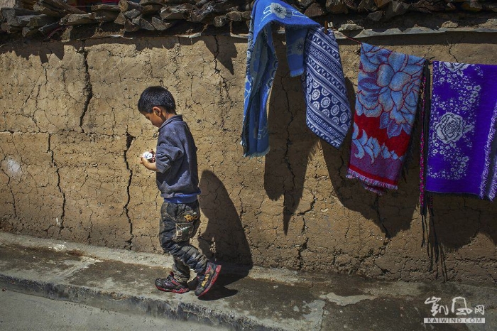 独自在围墙边玩耍的小男孩。留守儿童是羌寨中常见的情景。