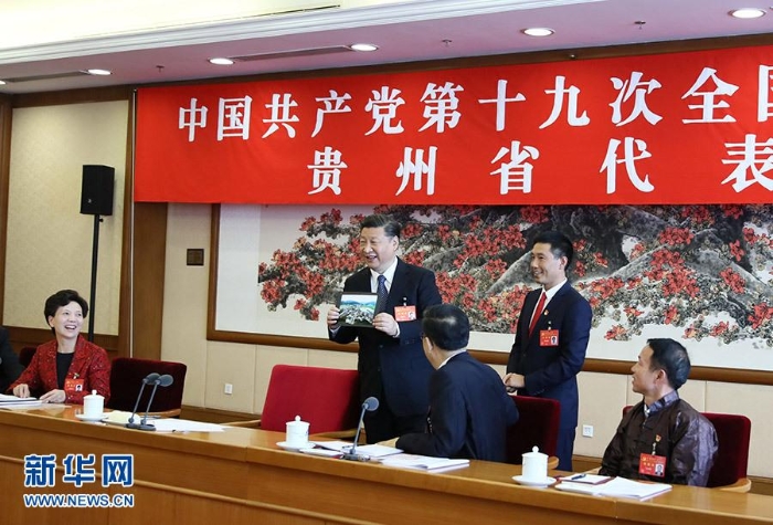 10月19日，习近平同志参加党的十九大贵州省代表团讨论。这是遵义市播州区花茂村党总支书记潘克刚将一幅鸟瞰村子新貌的照片送到习近平面前。习近平起身接过照片，边看边称赞：“这是风景画，很漂亮！” 新华社记者 兰红光 摄