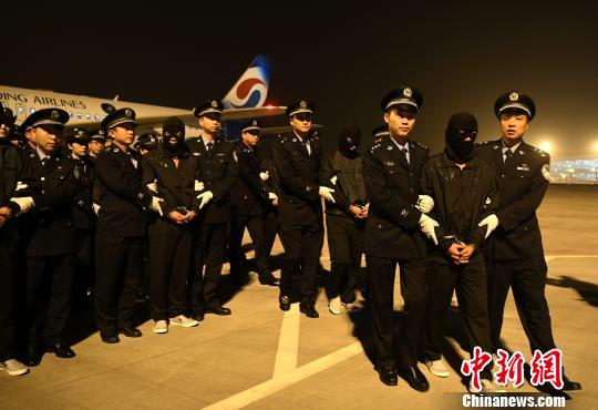 图为民警押解着嫌犯离开重庆江北国际机场。　陈超 摄