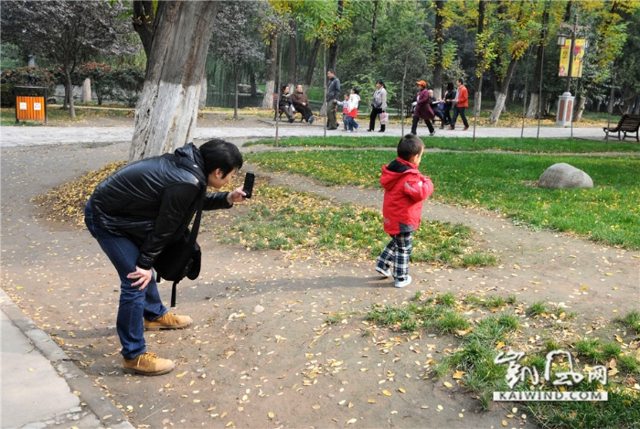 2013年11月3日，西安市兴庆公园，父亲用手机给孩子拍照。