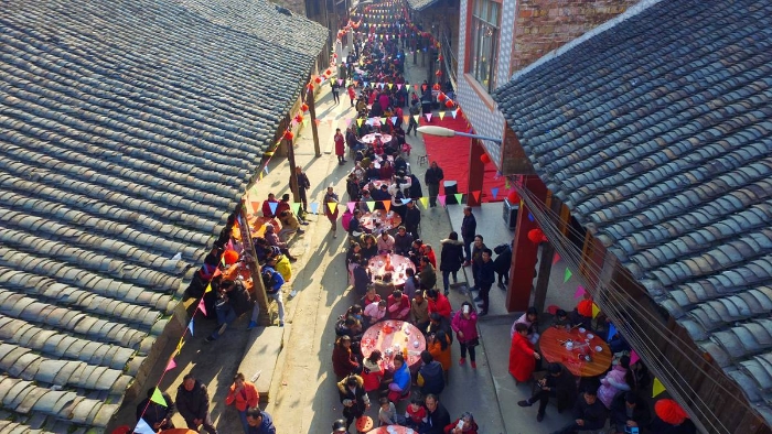 图1：2月11日，广西柳州市融安县板榄镇社区，居民正围坐在一起吃“长街宴”。（谭凯兴 摄）