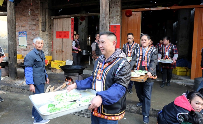 图13：2月11日，广西柳州市融安县板榄镇社区，工作人员将“长街宴”的菜品端给居民。（谭凯兴 摄）