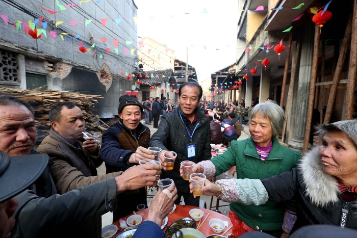 图14：2月11日，广西柳州市融安县板榄镇社区，社区干部（中）给孤寡老人敬酒。（谭凯兴 摄）
