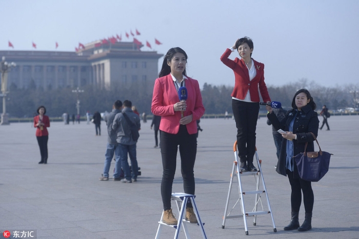 2017年3月3日全国两会在北京举行，政协开幕式之前，记者们站在场外踩着小梯子进行现场直播。潘之望/东方IC