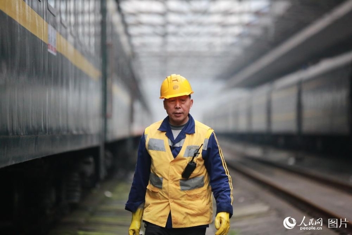 2月5日，在重庆北站站台下，每当火车鸣笛进站时，几位手拿铁钥匙、身穿黄马褂的工人都会站在轨道边等待。