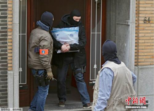 资料图：比利时警察戴面罩搜查布鲁塞尔恐袭案嫌犯公寓。