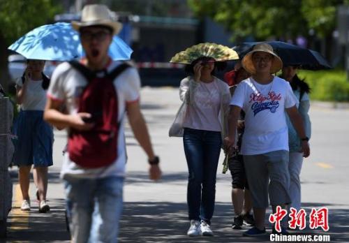 7月13日，厦门市民行走在热浪滚滚的路面上。　张斌 摄