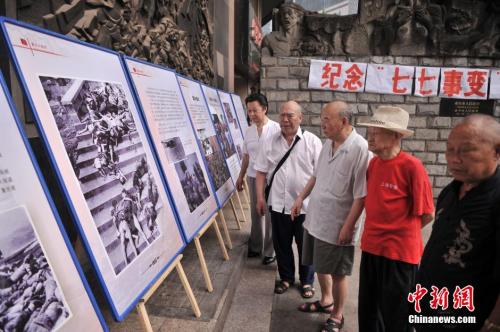 资料图：2014年7月7日，全民族抗战爆发77周年纪念日。重庆大轰炸经历者和遇难者家属在大轰炸遗址前举行“七七事变”全民族抗战爆发77周年纪念活动。图为遇难者的家属和市民参观重庆大轰炸图片展。陈超 摄