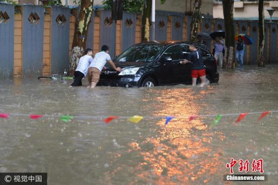 9日20时江苏省气象局启动重大气象灾害(暴雨)Ⅳ级应急响应，今天(10日)08时45分江苏省气象台升级发布暴雨黄色预警信号。预计今天白天南京、镇江、扬州中南部、泰州、常州、无锡、苏州北部、南通等地的大部地区有6小时50毫米以上降雨，局部100毫米以上，并可能伴有强雷电、短时强降水和雷暴大风等强对流天气。图为6月10日，南京市雨花台区，几个男子推着抛锚的汽车。文字来源：中国天气网 图片来源：视觉中国