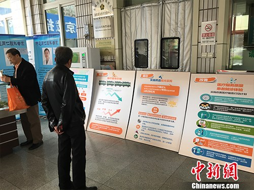 资料图：北京普仁医院外，有人在细读医改宣传板。汤琪 摄