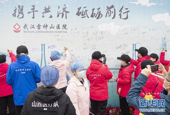 3月29日，在武汉雷神山医院举行的集中撤离仪式上，医护人员签名留念。 当日，武汉雷神山医院举行首批外省医疗队集中撤离仪式，送别即将踏上归途的辽宁、上海、吉林、广东、山西、河北医疗队的1090名医护人员。 新华社记者 才扬 摄