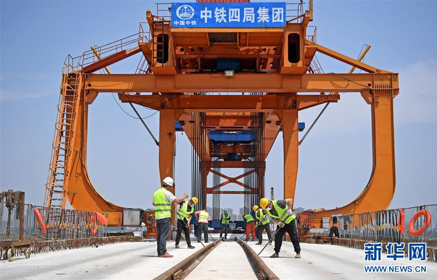 5月2日，在安九高铁江西段长江特大桥施工现场，施工人员在进行运梁上桥作业。 “五一”假日期间，由中铁四局承建的安（庆）九（江）高铁江西段项目部对施工节点重新规划，根据返岗人员工种相应开展分项工程施工，加紧架桥建设，确保完成工程目标。 新华社记者 万象 摄