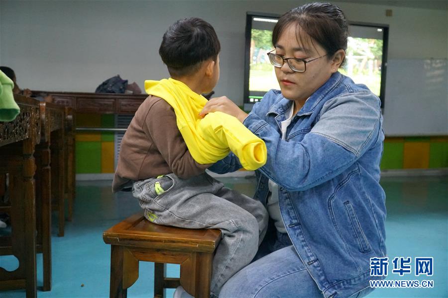 在青海省西宁市城西区的彩虹塔心智障碍儿童服务中心，德措卓玛老师手把手地教蓉蓉拼雪花片积木（5月29日摄）。 新华社记者 张子琪 摄