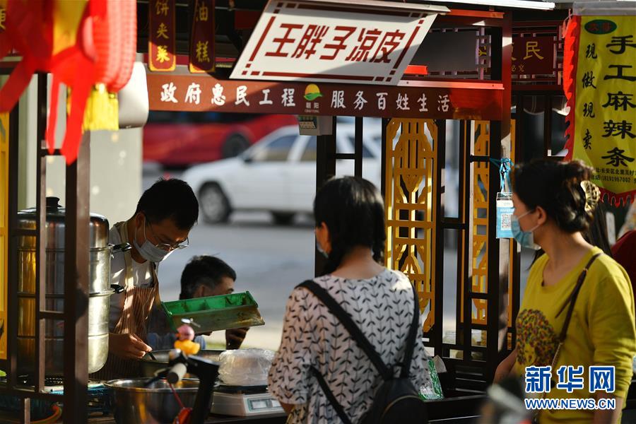 6月2日，在西安市曲江新区金滹沱二路，市民在临时摊区选购食品。 近日，陕西省出台《陕西省促进市场消费积极应对新冠肺炎疫情影响若干措施》，在确保安全的情况下，允许城区临街店铺出店经营，允许在居民居住集中区开辟临时摊点摊区，允许流动商贩在一定时间和区域占道经营。 西安市曲江新区城市管理部门在做好疫情防控工作的前提下，在固定时间、固定区域开辟临时摊点，积极推进“地摊经济”发展。 新华社记者 张博文 摄