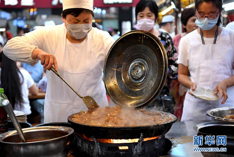 6月2日，在河南省开封市鼓楼夜市，一名小吃摊主在制作传统小吃炒凉粉。 近日，河南省开封市鼓楼夜市在关闭4个月后恢复开放。近200个摊位整齐排开，各色小吃琳琅满目，烹炒的火苗、蒸腾的热气、不绝于耳的叫卖声……古色古香的广场上重现欢腾的烟火气。 新华社记者 李安 摄