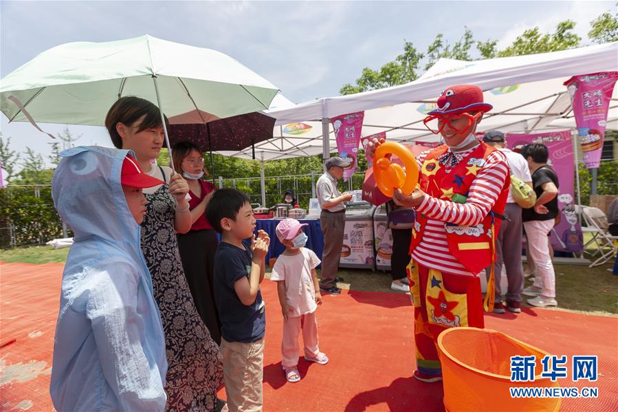 6月7日，小朋友在购物节上与打扮成小丑的气球艺人互动。新华社记者 黄安琪 摄