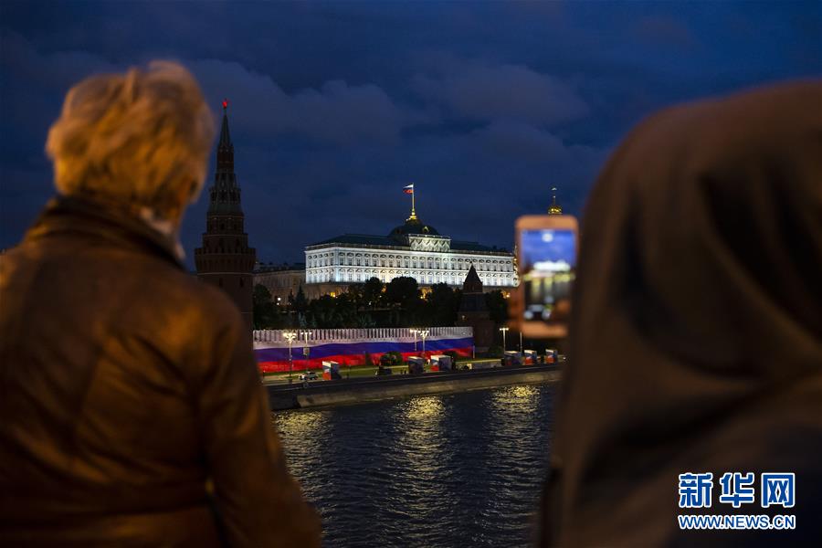 6月12日，人们在俄罗斯首都莫斯科观看克里姆林宫红墙外的灯光秀。