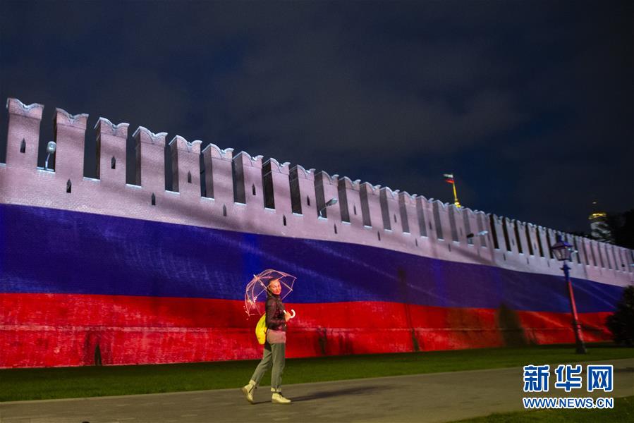6月12日，一名女子从俄罗斯首都莫斯科的克里姆林宫红墙前走过。