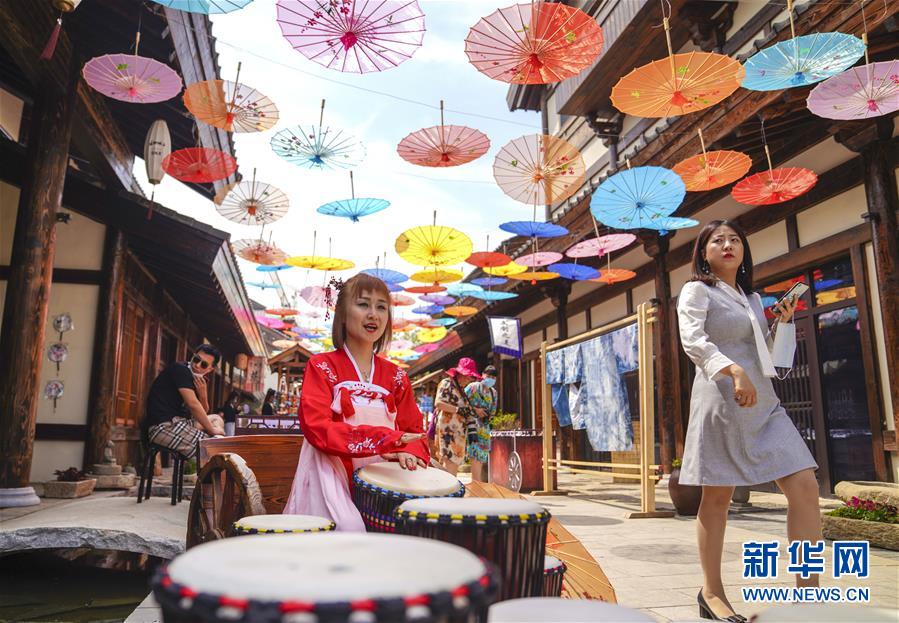 6月13日，在长春市世茂莲花山小镇宽厚里商街，一名古装爱好者演奏手鼓。 当日是“文化和自然遗产日”。吉林长春首届莲花山消夏生活节在世茂莲花山小镇举行。活动将非遗展示与假日消暑休闲相结合，让游人在“古色古香”的油纸伞巷中品传统文化魅力，享夏日休闲惬意。 新华社记者 许畅 摄