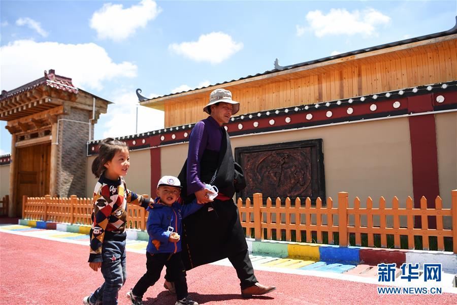 6月20日，在甘南藏族自治州碌曲县尕海镇尕秀村，村民格日扎西（右一）带着孩子从村里走过。  新华社记者 陈斌 摄