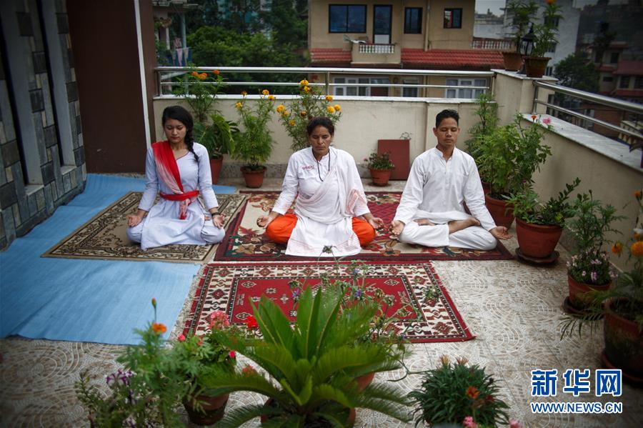 月21日，在尼泊尔加德满都，一家人在自家阳台练习瑜伽。 每年的6月21日被联合国大会定为国际瑜伽日。 新华社发（苏拉韦·什雷斯塔摄）