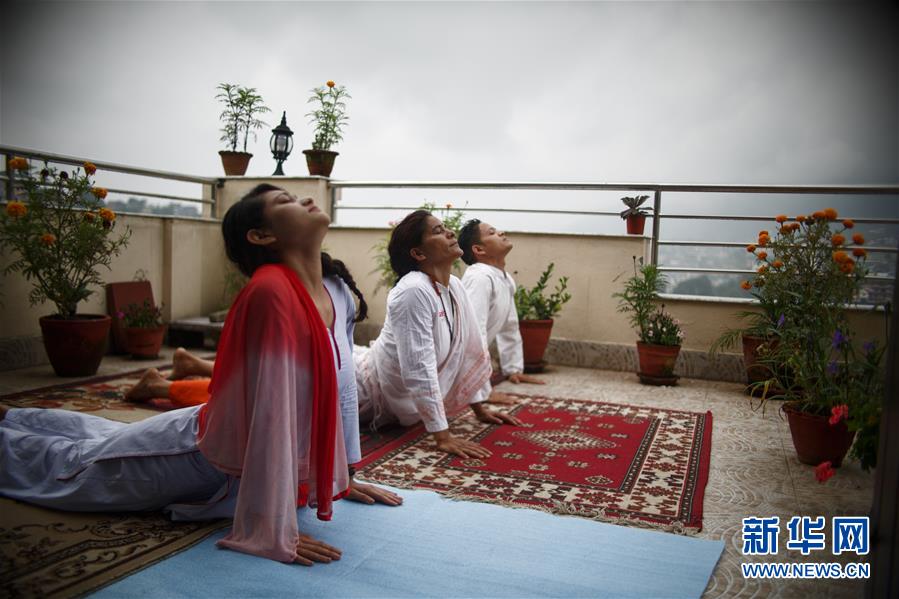 6月21日，在尼泊尔加德满都，一家人在自家阳台练习瑜伽。 每年的6月21日被联合国大会定为国际瑜伽日。 新华社发（苏拉韦·什雷斯塔摄）