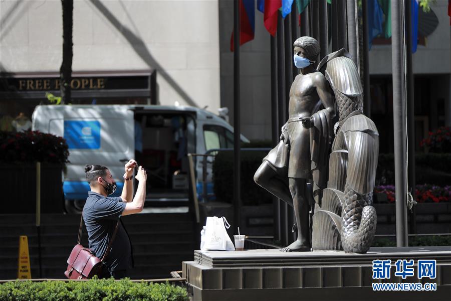 6月22日，在美国纽约洛克菲勒中心，一名男子拍摄“戴”口罩的雕像。 美国约翰斯·霍普金斯大学22日发布的新冠疫情最新统计数据显示，美国累计死亡病例超过12万例。 新华社记者王迎摄