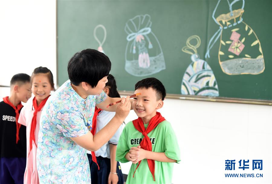 6月23日，浙江省诸暨市山下湖镇中心小学校长王国英为一年级学生点雄黄。 新华社记者 韩传号 摄