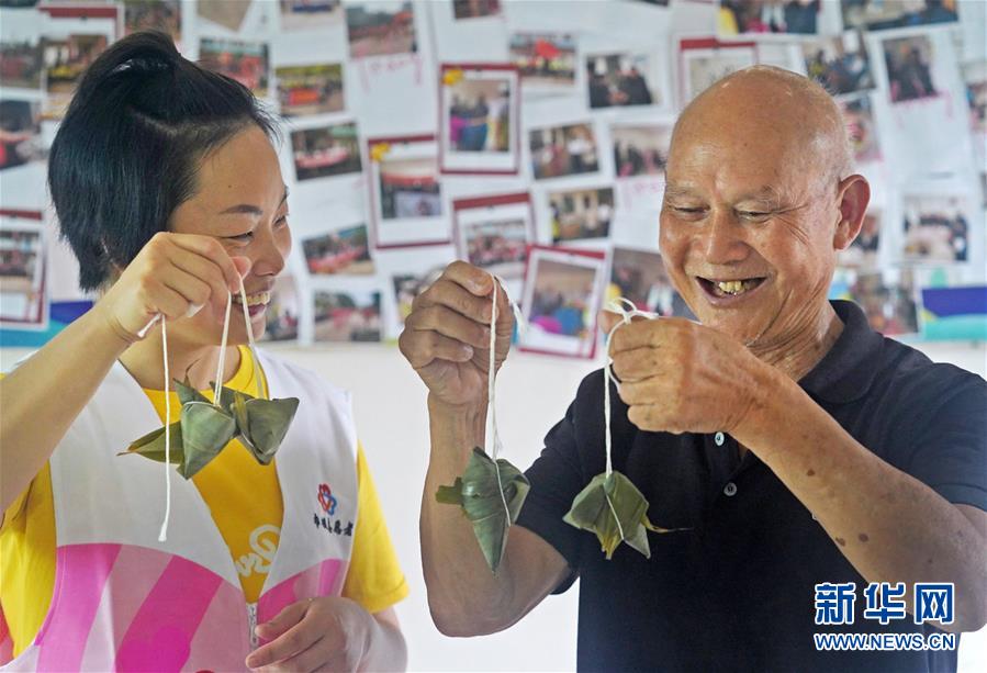 6月23日，在江西省南昌县三江镇一家敬老院，志愿者（左）和老人一起展示包好的粽子。新华社记者 万象 摄