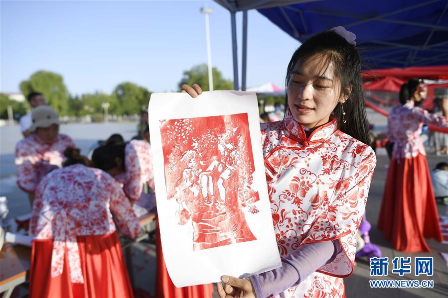 6月23日，一位剪纸参赛者展示自己的剪纸作品。 当日，全国最大的易地生态移民扶贫集中安置区宁夏吴忠市红寺堡区举行迎端午活动，邀请各乡镇的民间剪纸、刺绣艺人现场比拼传统技艺，居民现场参与包粽子大赛，共迎端午节的到来。 新华社记者 王鹏 摄