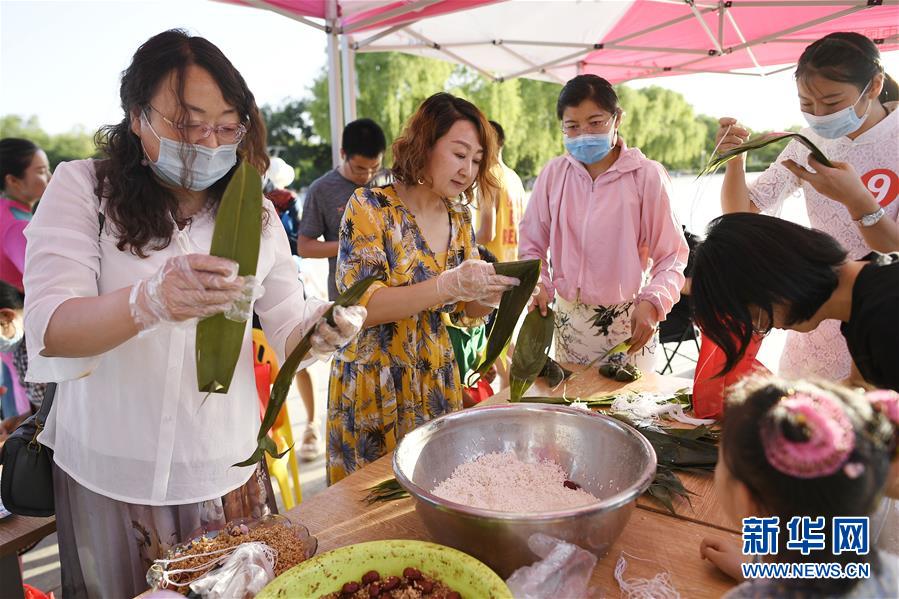 6月23日，居民在活动现场参加包粽子比赛。 当日，全国最大的易地生态移民扶贫集中安置区宁夏吴忠市红寺堡区举行迎端午活动，邀请各乡镇的民间剪纸、刺绣艺人现场比拼传统技艺，居民现场参与包粽子大赛，共迎端午节的到来。 新华社记者 王鹏 摄
