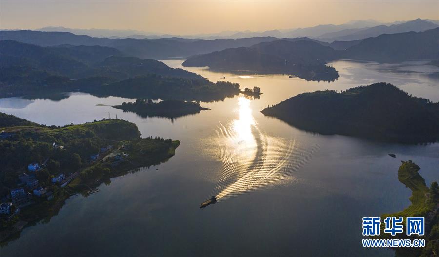6月24日，一条船驶过夕阳下的瀛湖湖面（无人机照片）。新华社记者 陶明 摄