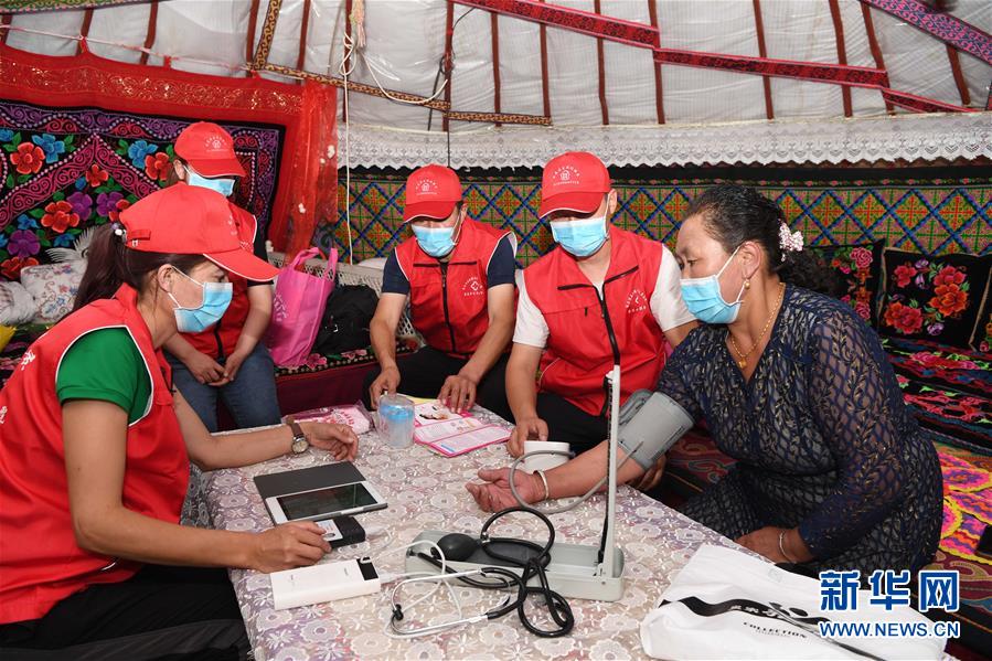 6月20日，新疆布尔津县也格孜托别乡卫生院全科医生哈纳提别克·沙旦（右二）和医生布勒布勒古丽·金恩斯汗（左一）等给牧民吉木斯古丽·卡依索勒坦检查身体。  新华社记者 沙达提 摄