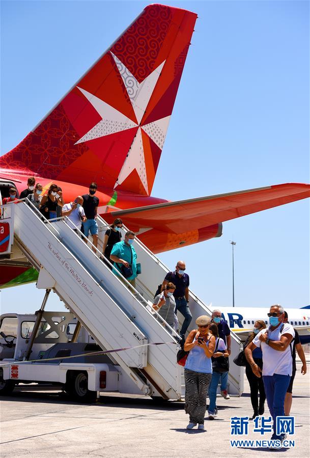 7月1日，在马耳他国际机场，旅客走下飞机。 马耳他国际机场于7月1日重新开放。 新华社发（乔纳森·博尔格摄）