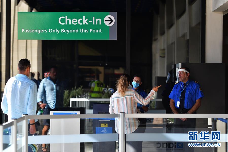 7月1日，在马耳他国际机场，佩戴防护装备的安保人员与旅客交流。 马耳他国际机场于7月1日重新开放。 新华社发（乔纳森·博尔格摄）