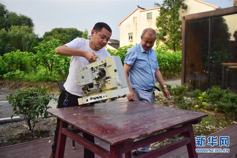 　6月30日，朱生荣（右）和儿子朱强（左）在马鸣村将军湖广场布置放映设备。在浙江嘉兴桐乡市洲泉镇马鸣村，王志华、朱文炳、朱生荣、朱强四代电影放映员，“接力”放映电影五十余年。一台放映机、几盘胶片、一面白墙，构成他们的“流动电影院”，“哒哒”的走带声转出了光影老味道，也转动了整村人的文化生活。 第四代放映人“85后”小伙朱强从小在幕布前长大，深受父辈影响。随着数字电影的普及，胶片电影逐渐退场。如今的他在马鸣电影馆、学校等场所进行教学、展示等活动，宣传电影文化。对他而言，一代接一代从事电影工作，就是为了承续传统。“师爷爷教我们认真放好每部电影，即便只有一位观众，我们也不会让它停机。”朱强说。新华社记者 郑梦雨 摄