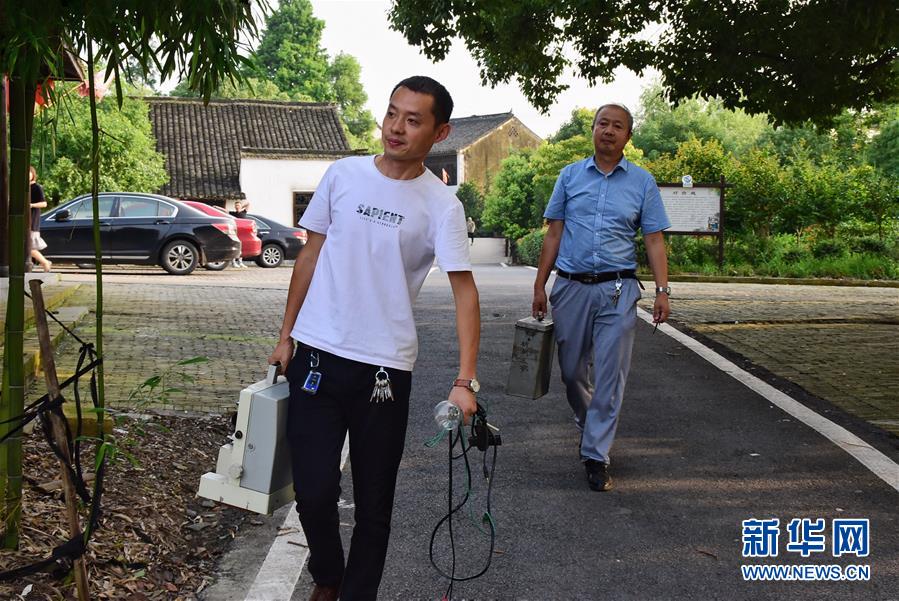 6月30日，朱生荣（右）和儿子朱强（左）携带放映设备来到马鸣村将军湖广场。新华社记者 郑梦雨 摄