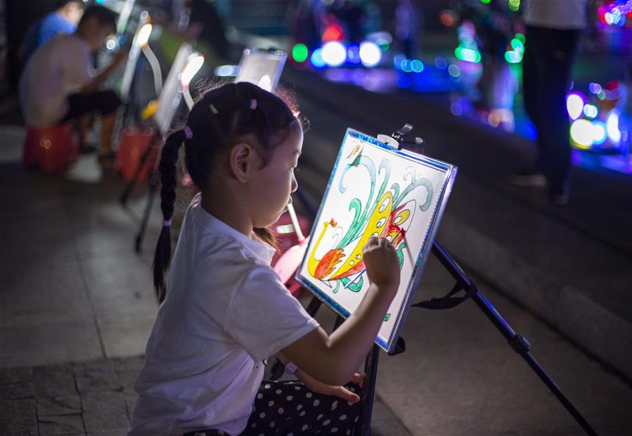 7月4日，在江苏省金湖县荷花广场，小朋友在夜市绘画区绘画。 江苏省淮安市金湖县位于江苏省中部，境内白马湖、宝应湖、高邮湖三面环绕。近年来，当地发挥其独特的地理区位优势，打造出金湖龙虾广场、尧帝古城小吃街、荷花广场便民服务点等一批特色区域，丰富当地群众夜生活。 新华社发（汤德宏 摄）