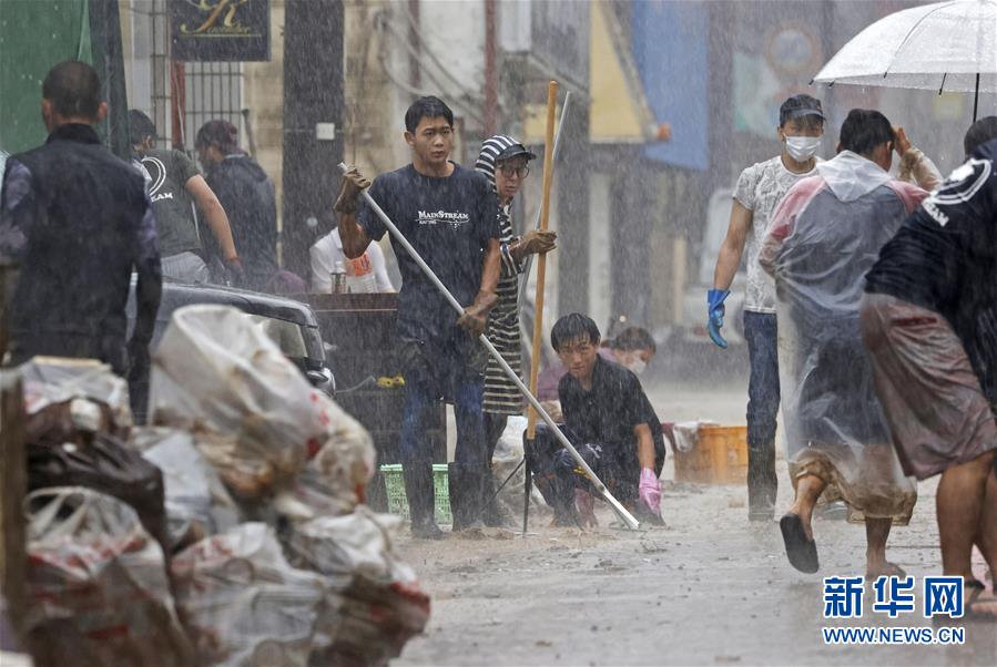 7月7日，日本熊本县人吉市居民在大雨中清理街道。 受停滞的梅雨锋面影响，日本九州地区北部7日继续遭遇强降雨天气。迄今，九州因暴雨引发的洪水泛滥、山体滑坡造成的死亡人数升至55人，另有13人失踪。 新华社/共同社