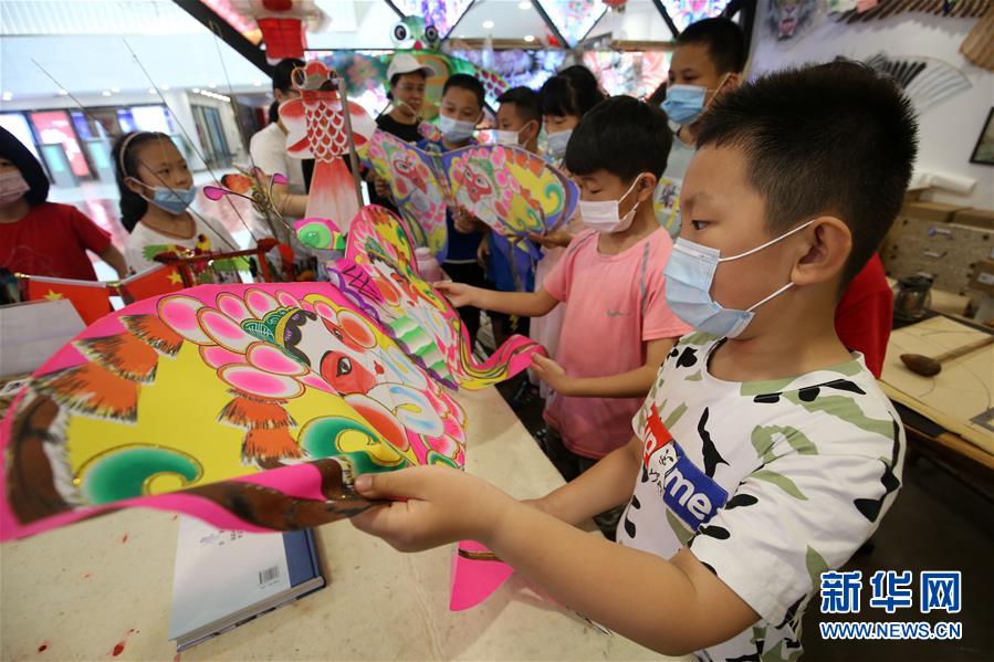 7月8日，山东省潍坊市潍城区城关街道十笏园社区的小朋友在了解潍坊风筝的制作工艺。 新华社发（张驰 摄）